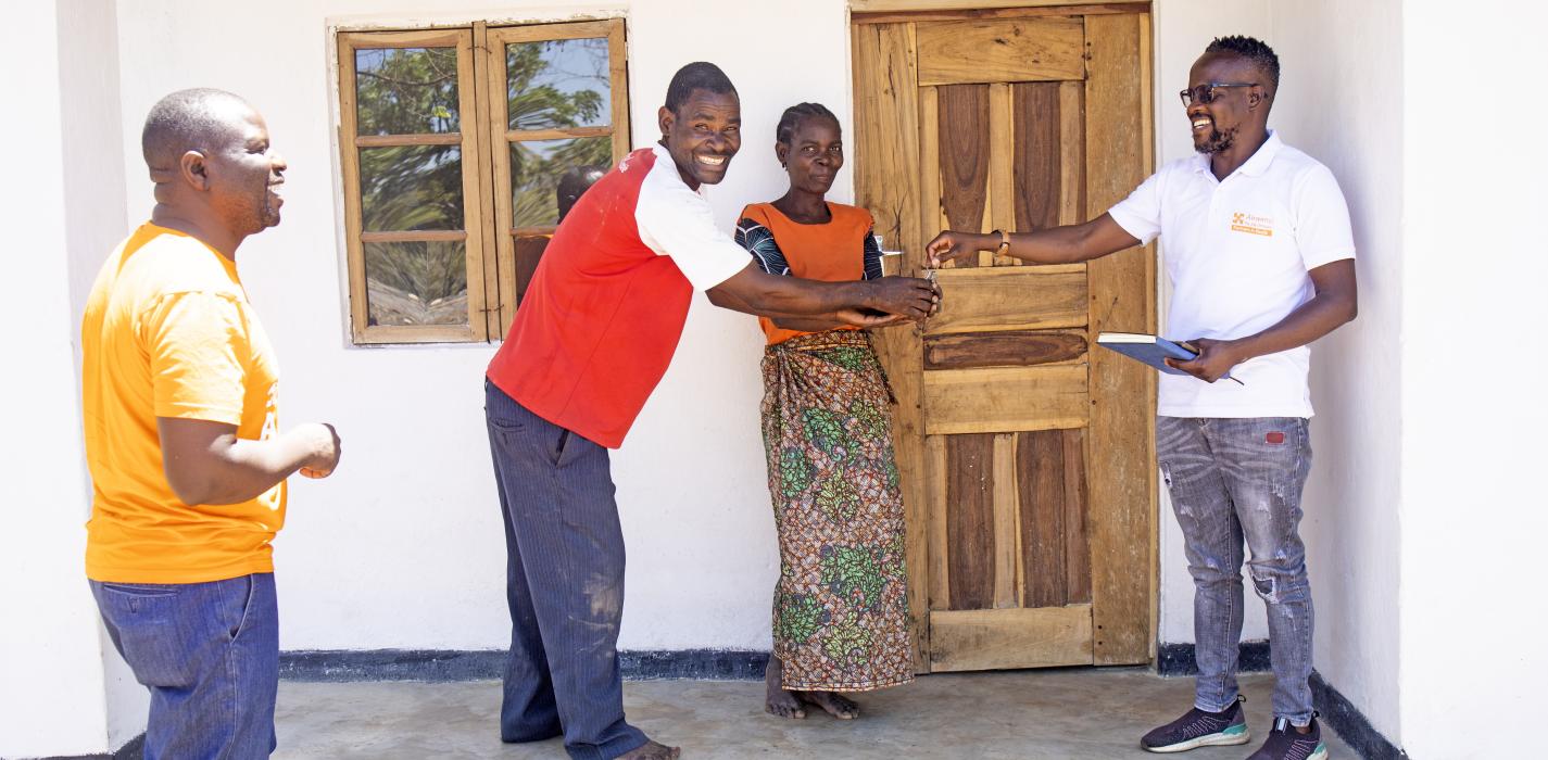 PIH staff handover a house to a beneficiary